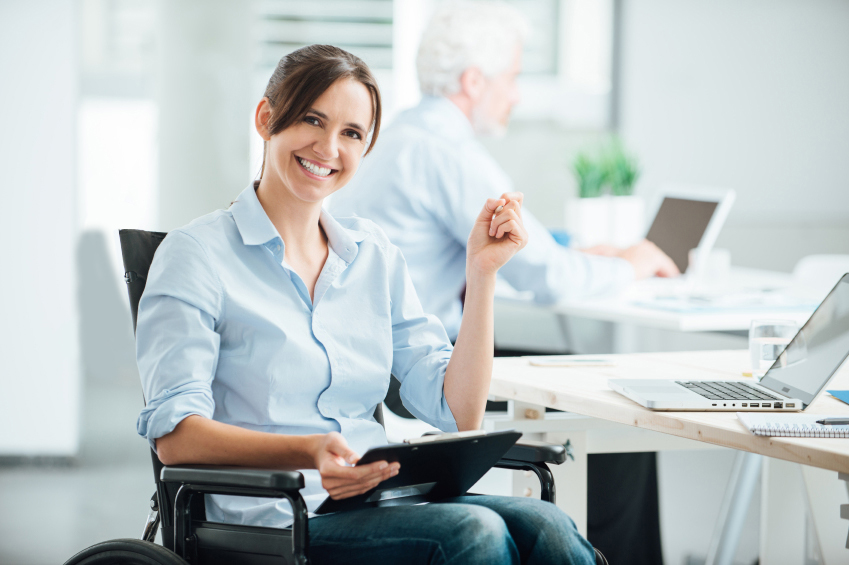 Smilende arbejdsom kvindelig kørestolsbruger på kontor - inspiration for andre kørestolsbrugere