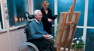 2 kunstere kigger på eget maleri, den ene kunstner arbejder fra en kørestol